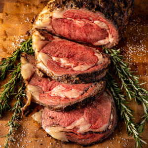 Sliced prime rib roast on a bed of fresh herbs.